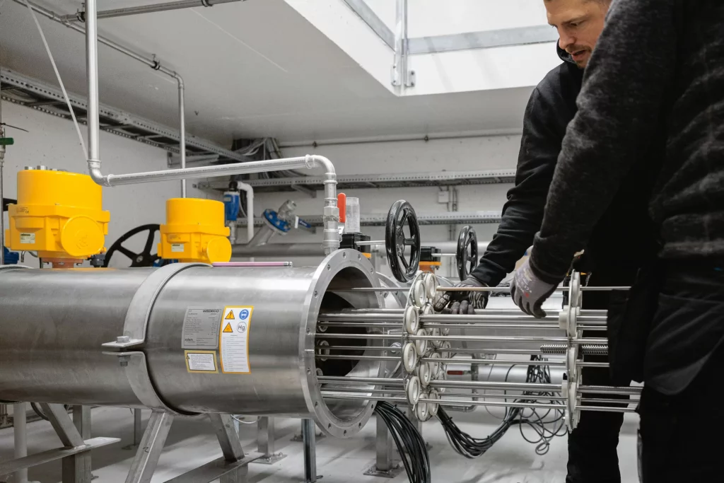 Servicetekniker från Aqua & Care drar ut UV-lampmodul för underhåll i en industriell UV-anläggning för vattenrening.